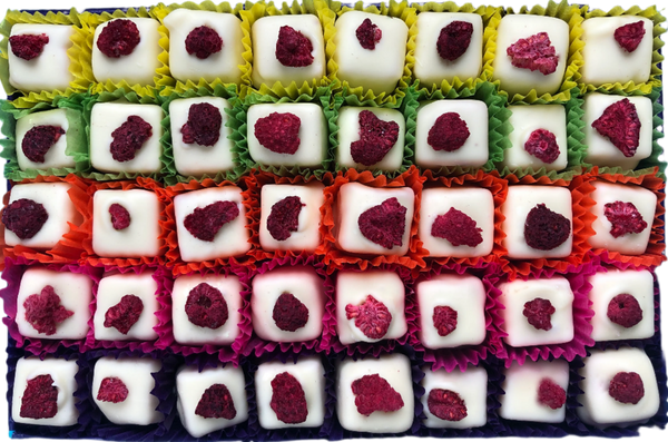 Open gift box of 40 Eton Mess chocolates in white chocolate and topped with a red freeze-dried raspberry. Each chocolate sits in a brightly coloured petit four case. Pictured from above