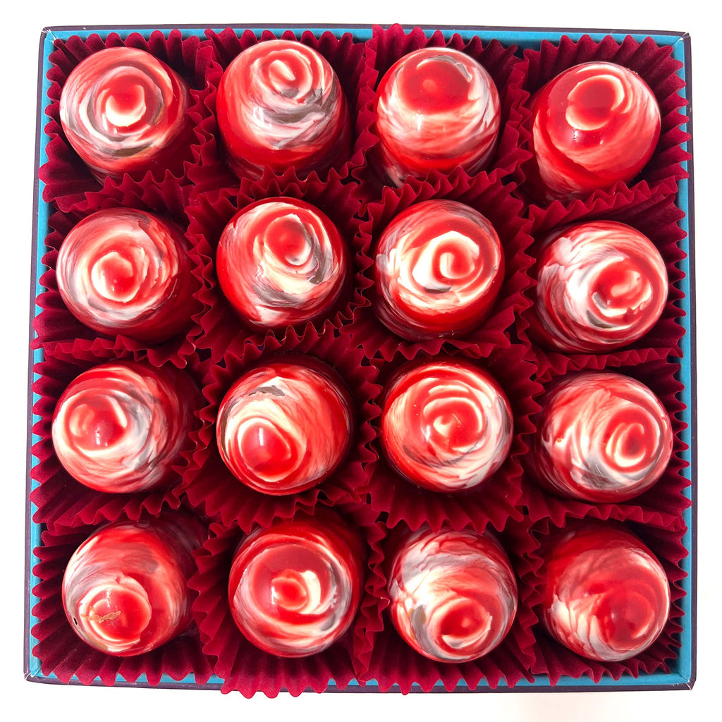 Square box of 16 handmade milk chocolate cream tea chocolates decorated with red and white cocoa butter swirls.