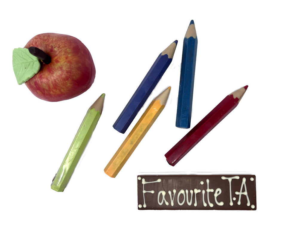Red and green chocolate apple, 5 coloured chocolate pencilsl and a chocolate bar saying Favourite TA. On a white background