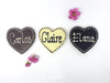3 chocolate hearts piped with Carlos, Claire and Elana. On a white background with 3 cherry blossom flowers.