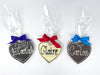 3 chocolate  hearts with names piped. Wrapped in cellophane and tied with satin ribbons. On a white background.
