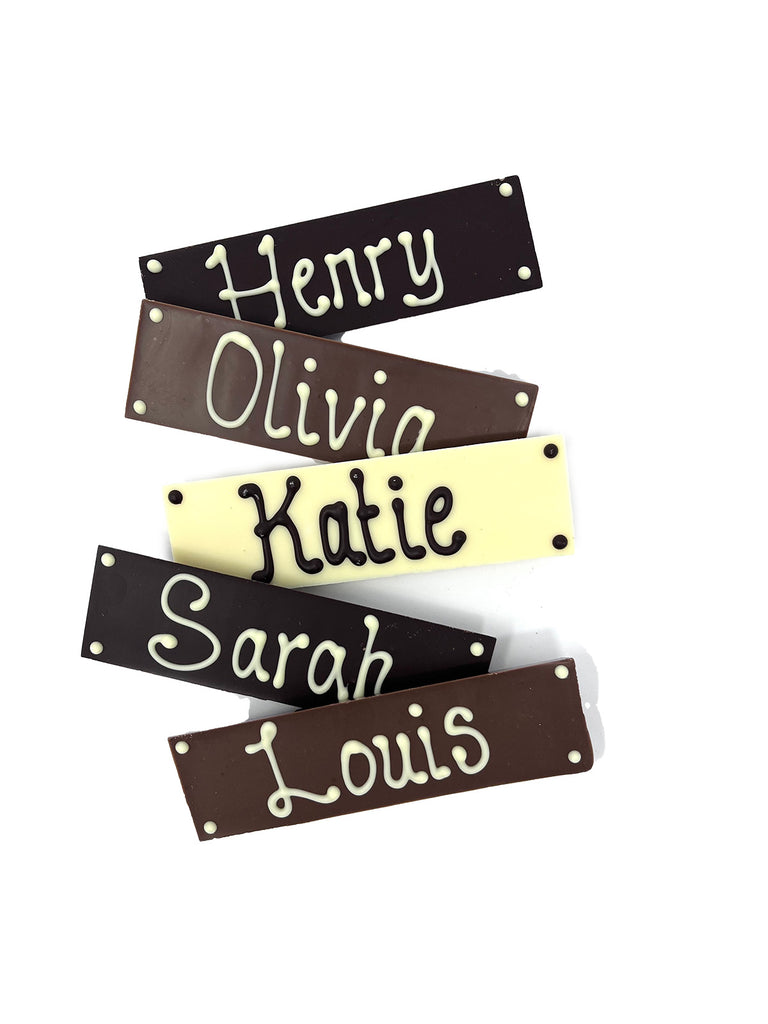 Five chocolate bars in milk, dark and white chocolate with names piped on. Arranged on a white background.
