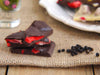 Lifestyle shot of small stack of dark chocolate shards with freeze dried strawberries and  black peppercorns