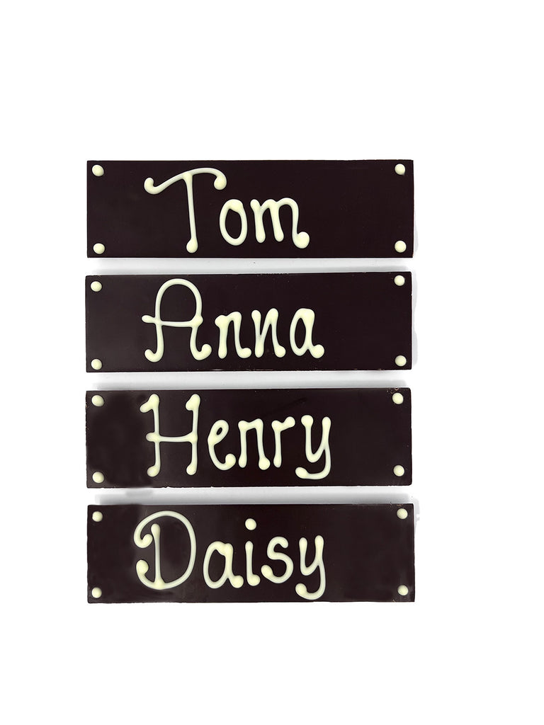 Four dark chocolate bars with names piped in white chocolate. On  white background.