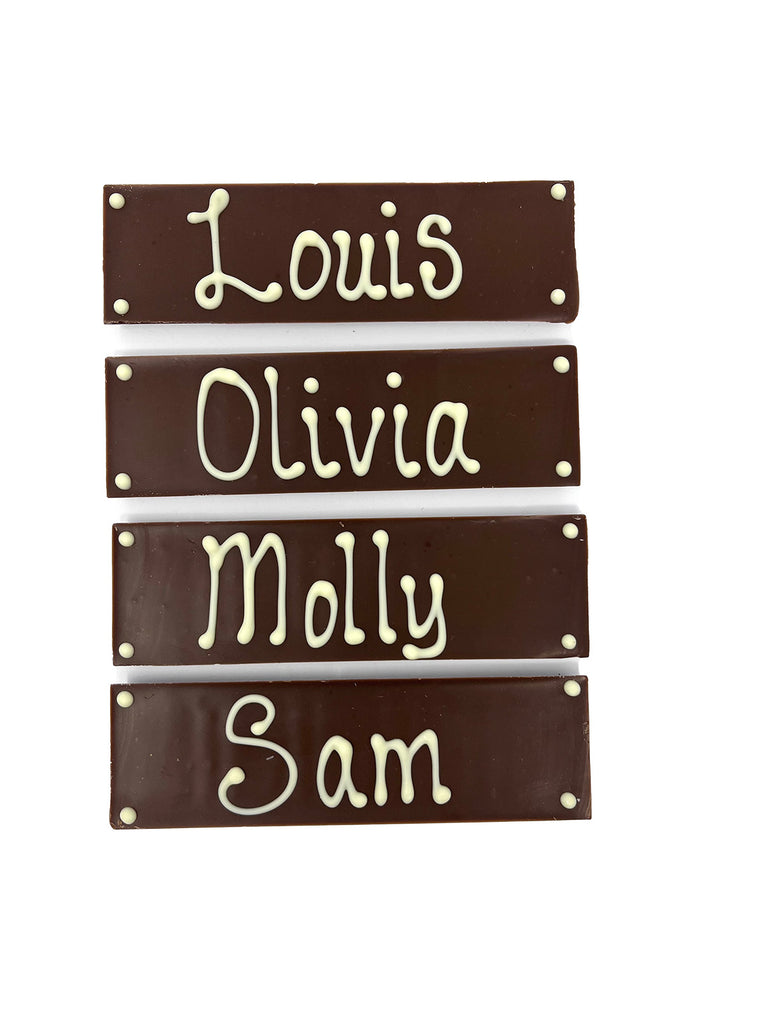 Four dark chocolate bars with names piped in white chocolate. On  white background.