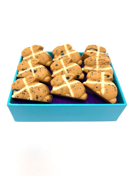 Open box of 9 blond chocolate hot cross bunnies filled with caramel. On a white background.