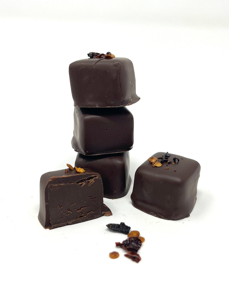 3 chocolates stacked and 1 cut open to show ganache inside. On a white background.