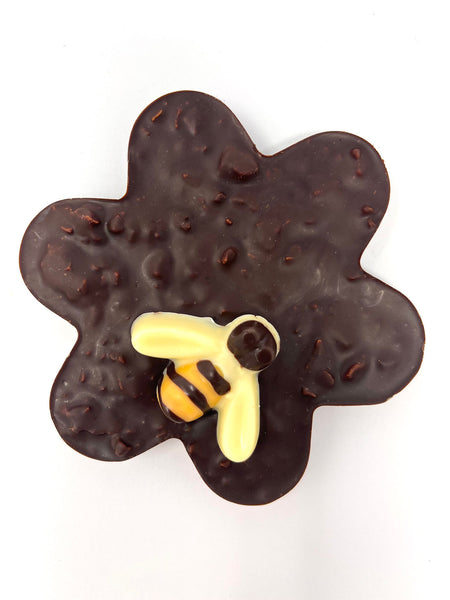 Dark chocolate flower with honeycomb. Decorated with a white chocolate bee. On a white background.