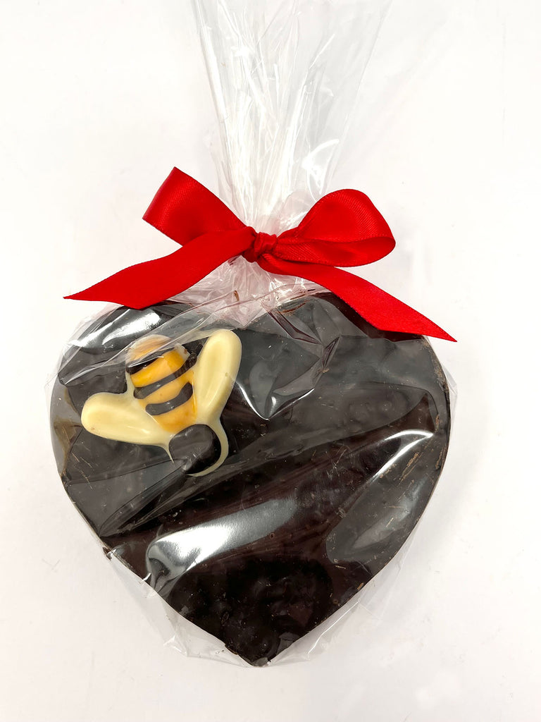 Dark Chocolate Heart with honeycomb decorated with a dark and white chocolate bumble bee. Wrapped in cellophane and tied with a red ribbon. View from above on a white background.