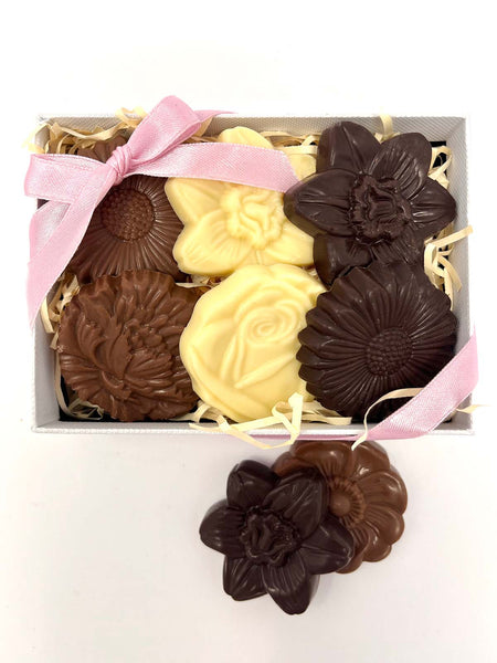 Box of chocolate flowers with a pink ribbon on a white background