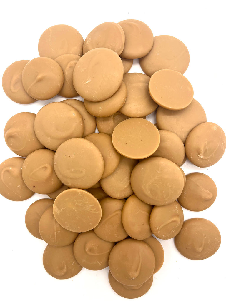 Pile of caramelised white chocolate buttons on a white background.