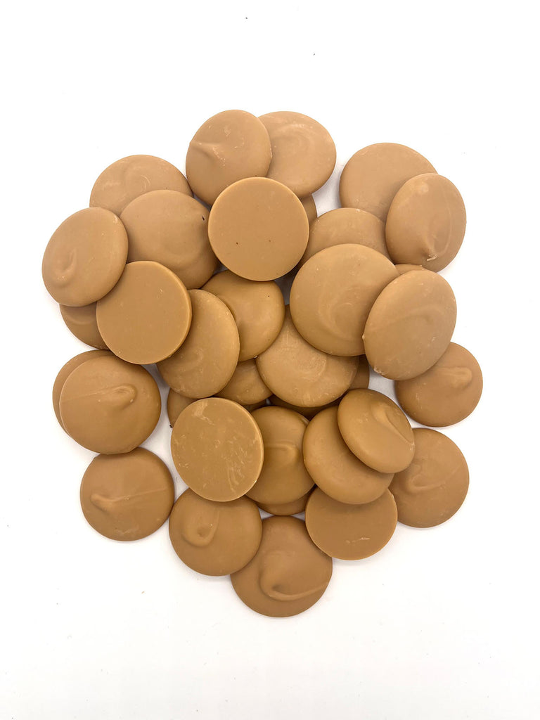Pile of caramelised white chocolate buttons on a white background