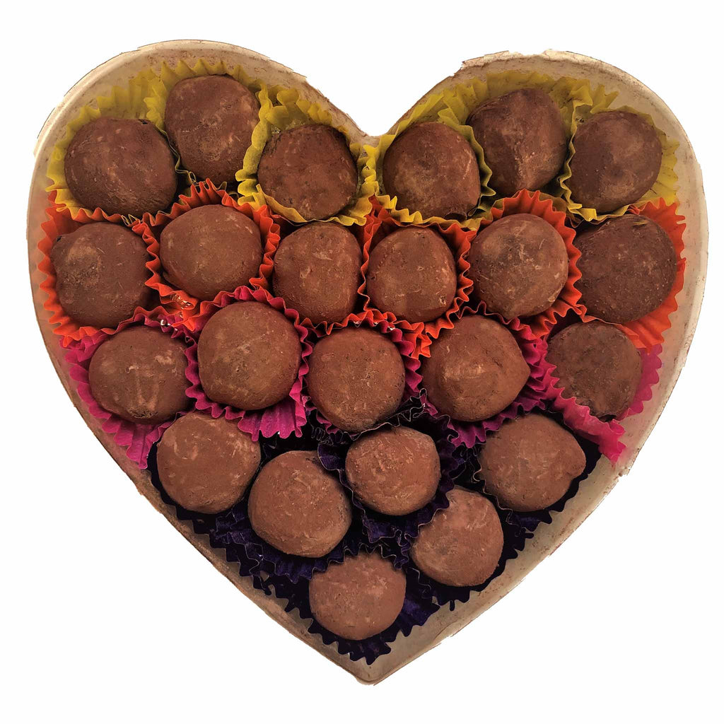 Heart-shaped box filled with chocolate truffles on a white background