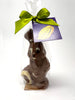MIlk chocolate bunny in a clear cellophane bag tied with a green satin ribbon. On a white background.