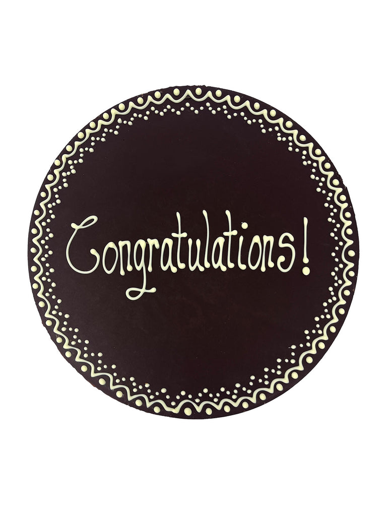 Dark chocolate plaque hand piped  with a decorative border and 'Congratulations!' text in white chocolate. On a white background.