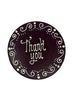 Dark chocolate plaque hand piped  with a decorative border and 'Thank you' text in white chocolate. On a white background.