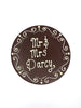 Milk chocolate plaque hand piped  with a decorative border and 'Mr & Mrs Darcy' text in white chocolate. On a white background