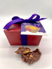Red gift box with purple bow and 'Gorvett & Stone' label, accompanied by a chocolate treat on a white background.