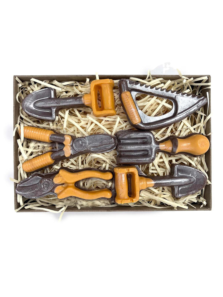 Gift box of miniature chocolate garden tools with orange handles. On a white background. 