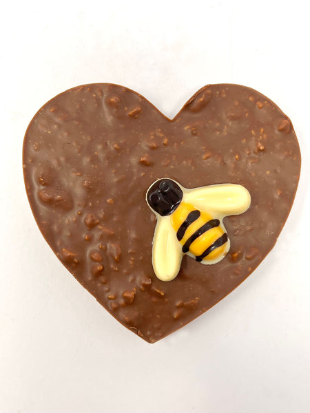 Milk Chocolate Heart with honeycomb decorated with a dark and white chocolate bumble bee. View from above on a white background.
