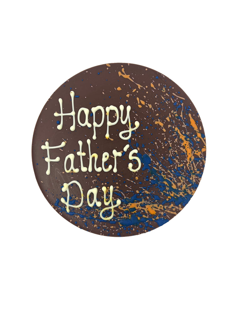 One round milk chocolate father's day plaque. Decorated with blue and orange splashes and piped Happy Father's Day. On a white background.