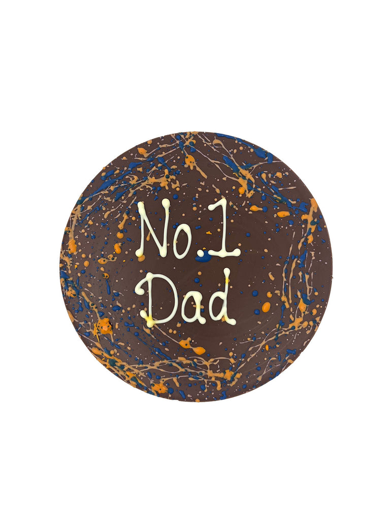 One round milk chocolate father's day plaque. Decorated with blue and orange splashes and piped No 1 Dad. On a white background.