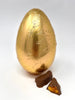Milk Chocolate Easter Egg in gold foil with two chunks of milk chocolate cinder toffee in the foreground.  On a white background.