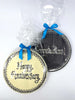 Two round chocolate plaques with Happy Anniversary and Congratulations! Wrapped in cellophane and tied with blue ribbon. On a a white background.