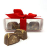 3 milk chocolate hearts in a clear box tied with red ribbon.
