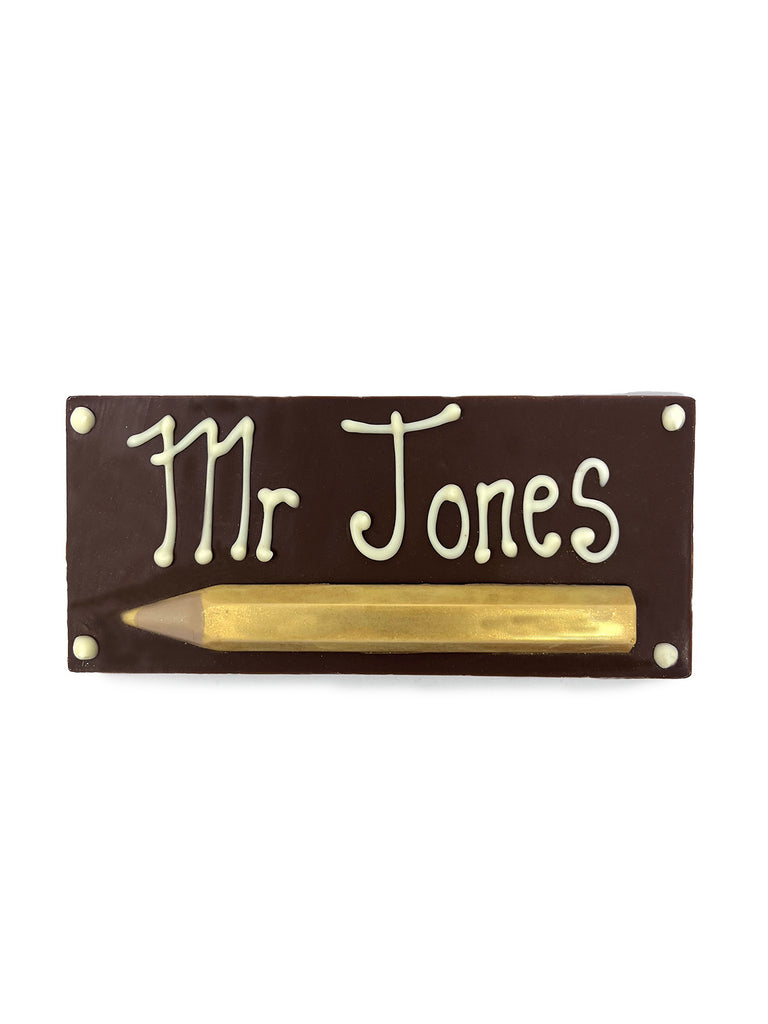 Chocolate Bar with piped decoration 'Mr Jones' and a gold chocolate pencil. On a white background.