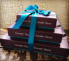 Pyramid of three Gorvett & Stone gift boxes tied with a blue satin ribbon.
