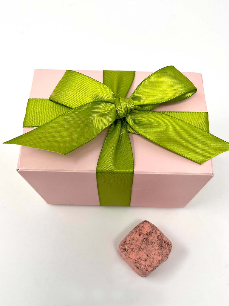 Pink gift box with a green ribbon on a white background