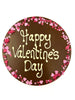 Milk chocolate round plaque on a white background. Plaque is piped with 'Happy Valentine's Day,  with a border of pink and red sugar hearts.
