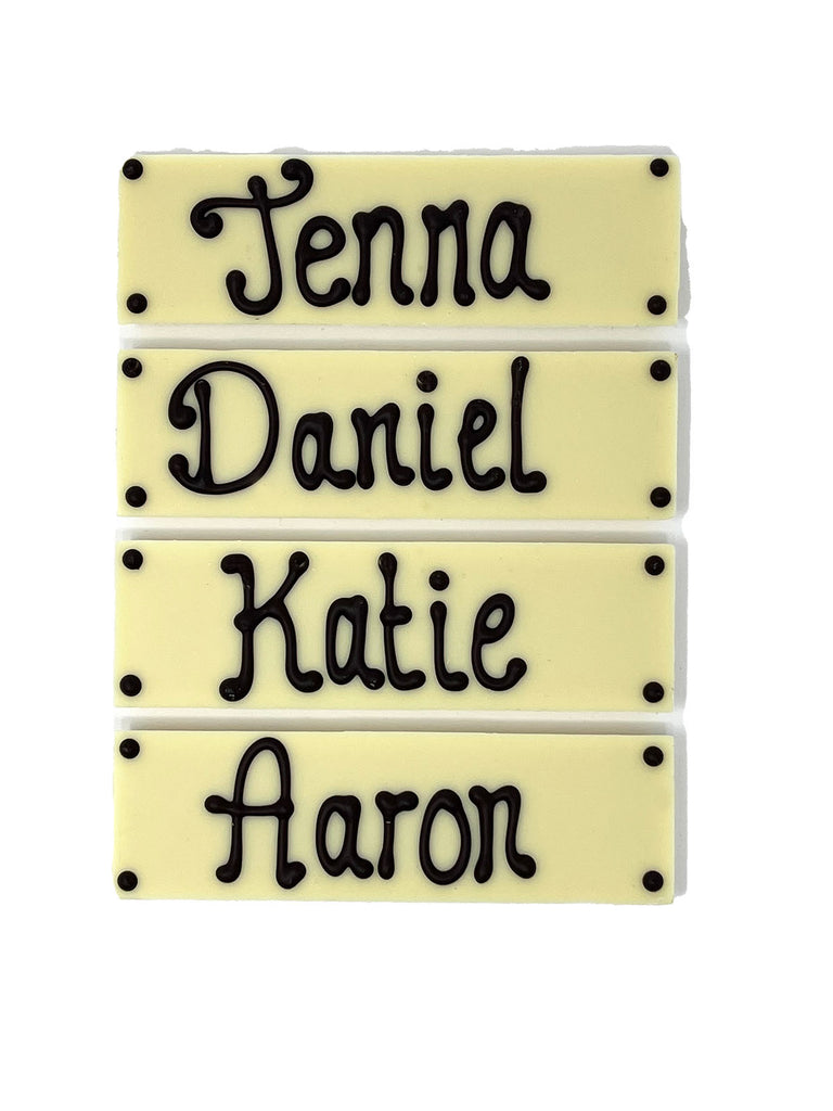 Four white chocolate bars with names piped in dark chocolate. On  white background.