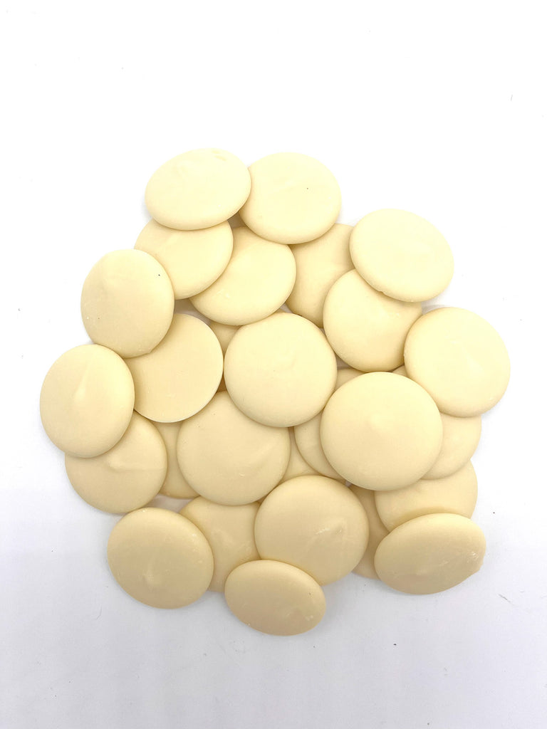 Pile of white chocolate buttons on a plain white background.