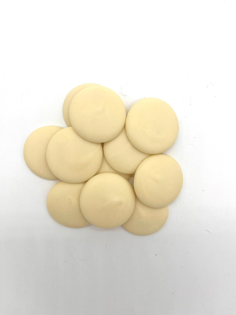 Pile of white chocolate buttons on a plain white background.