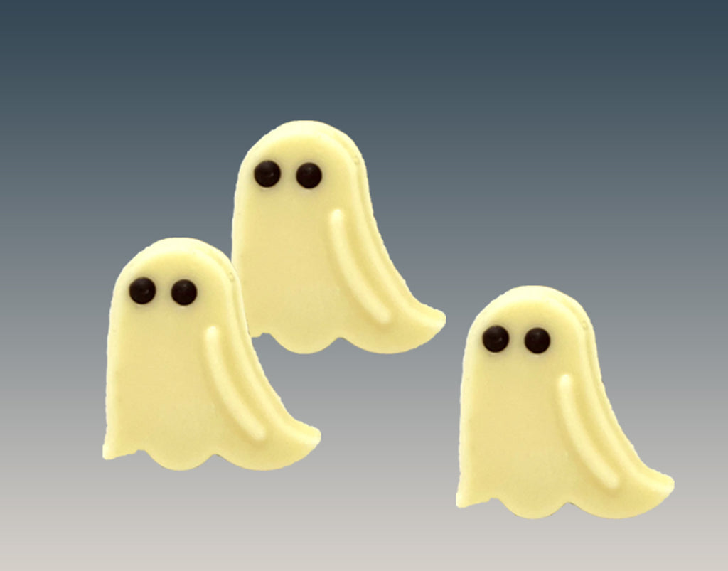 Three white chocolate ghosts on a grey background.