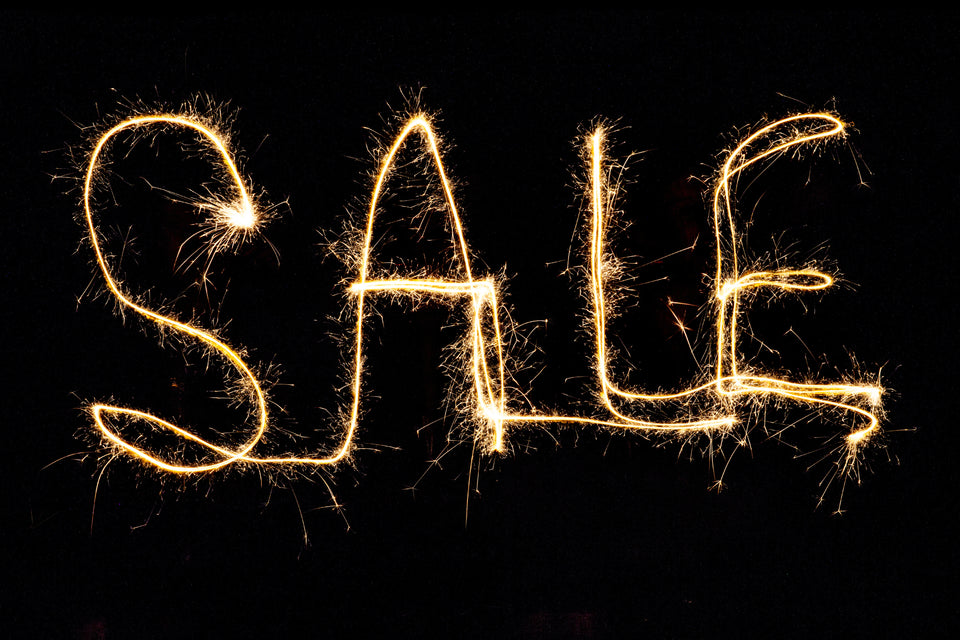 SALE word written in gold sparkly lights on a black background