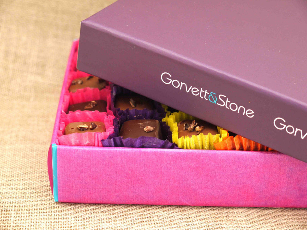Gift box of milk and dark chocolates partially covered with the box lid to show a sneak peak.